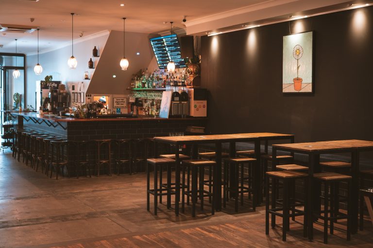 Spacious back bar with high tables and seating inside a function venue in Richmond
