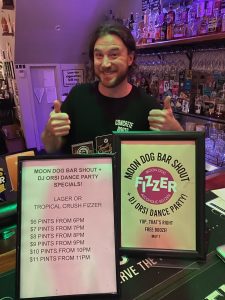 Smiling bartender at Concrete Boots in Richmond with drink specials for Moon Dog bar shout and DJ dance party.