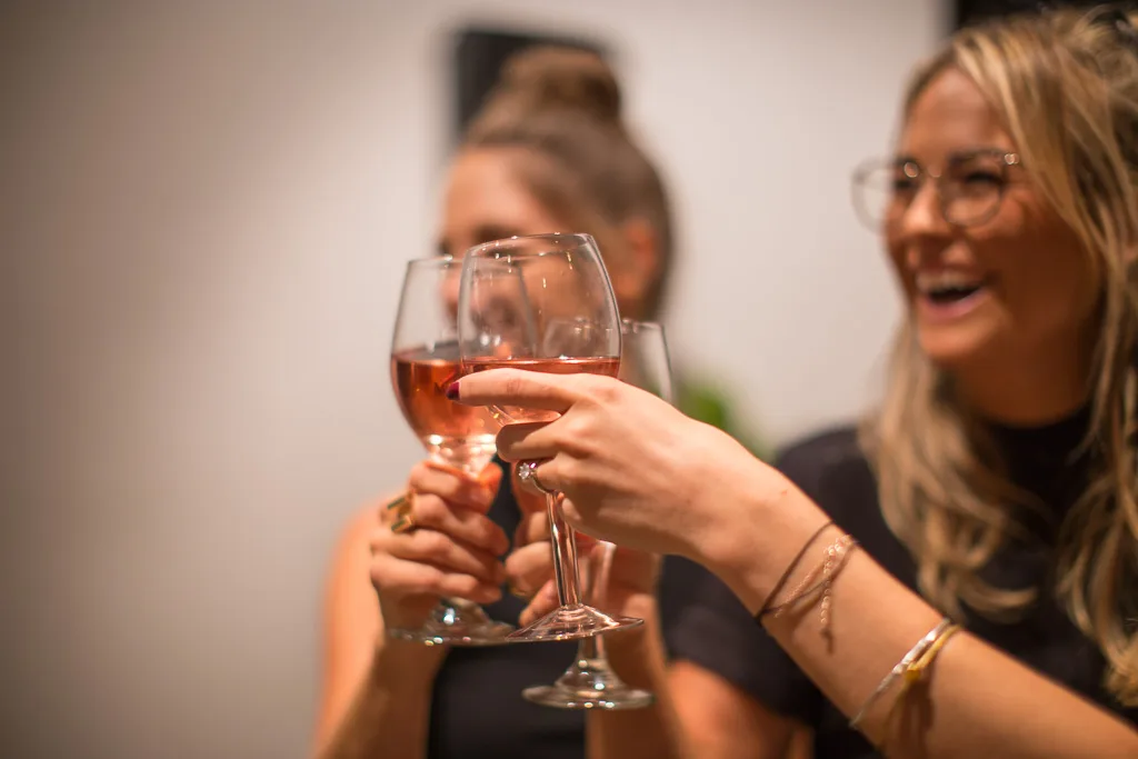 Two women toasting with glasses of rosé wine at a function venue in Richmond.